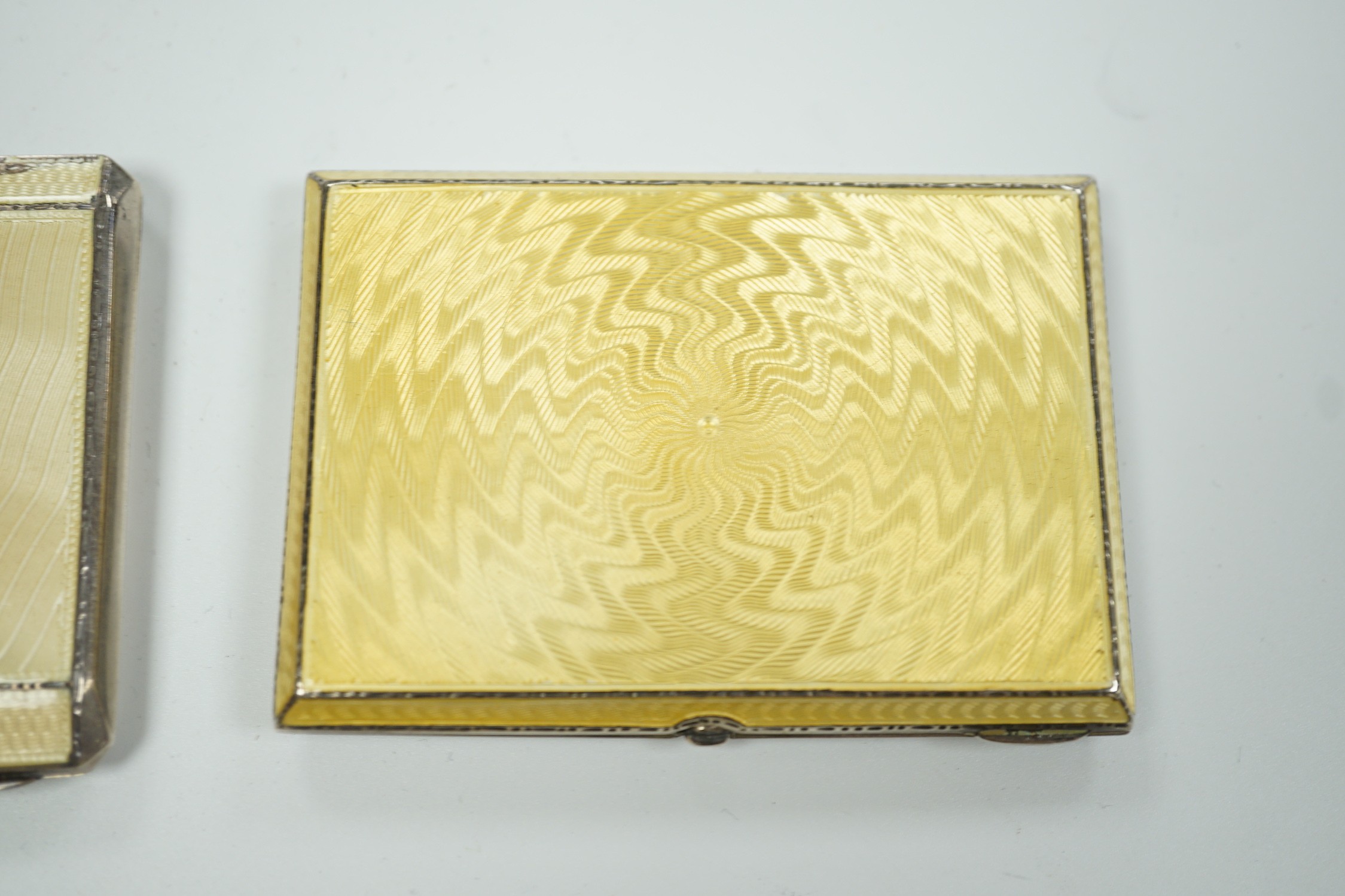 Two George V Art Deco silver and enamel cigarette cases, Birmingham, 1931 & 1932, largest 85mm (enamel a.f. on one) together with a German 800 standard white metal, cabochon emerald and rose cut diamond set compact/minau